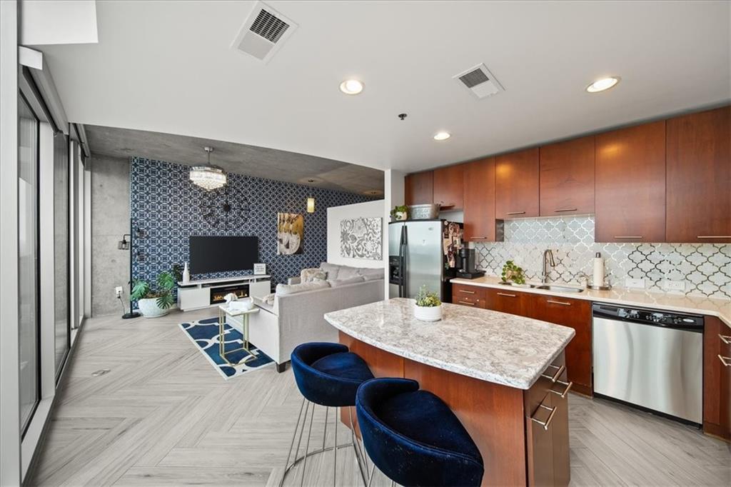 a kitchen with stainless steel appliances kitchen island granite countertop a table chairs in it and wooden floors