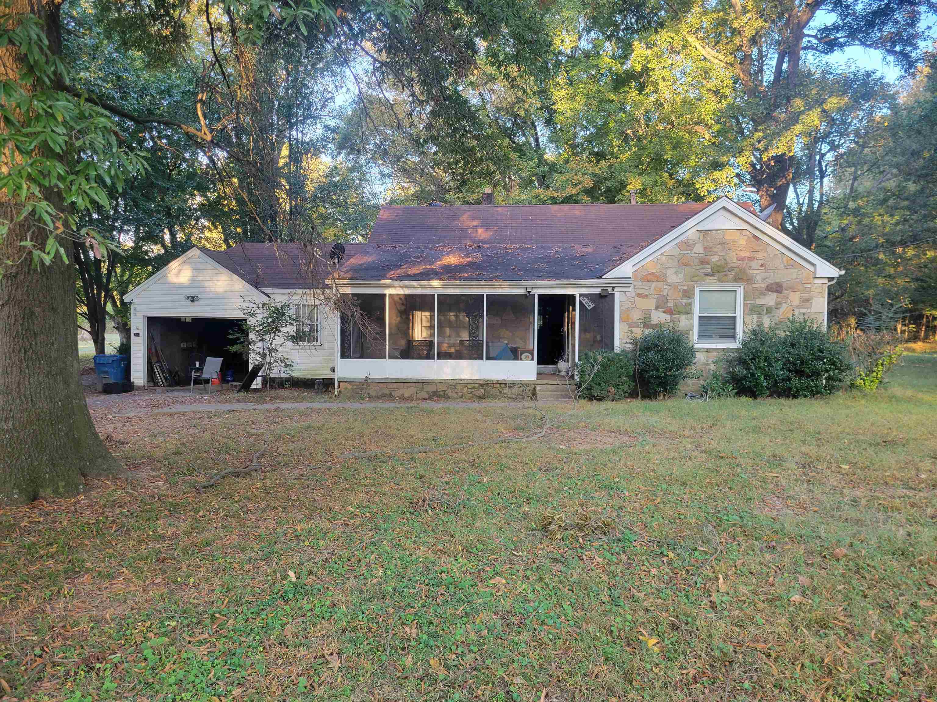 View of front of property featuring a garage, a front lawn, and a sunroom