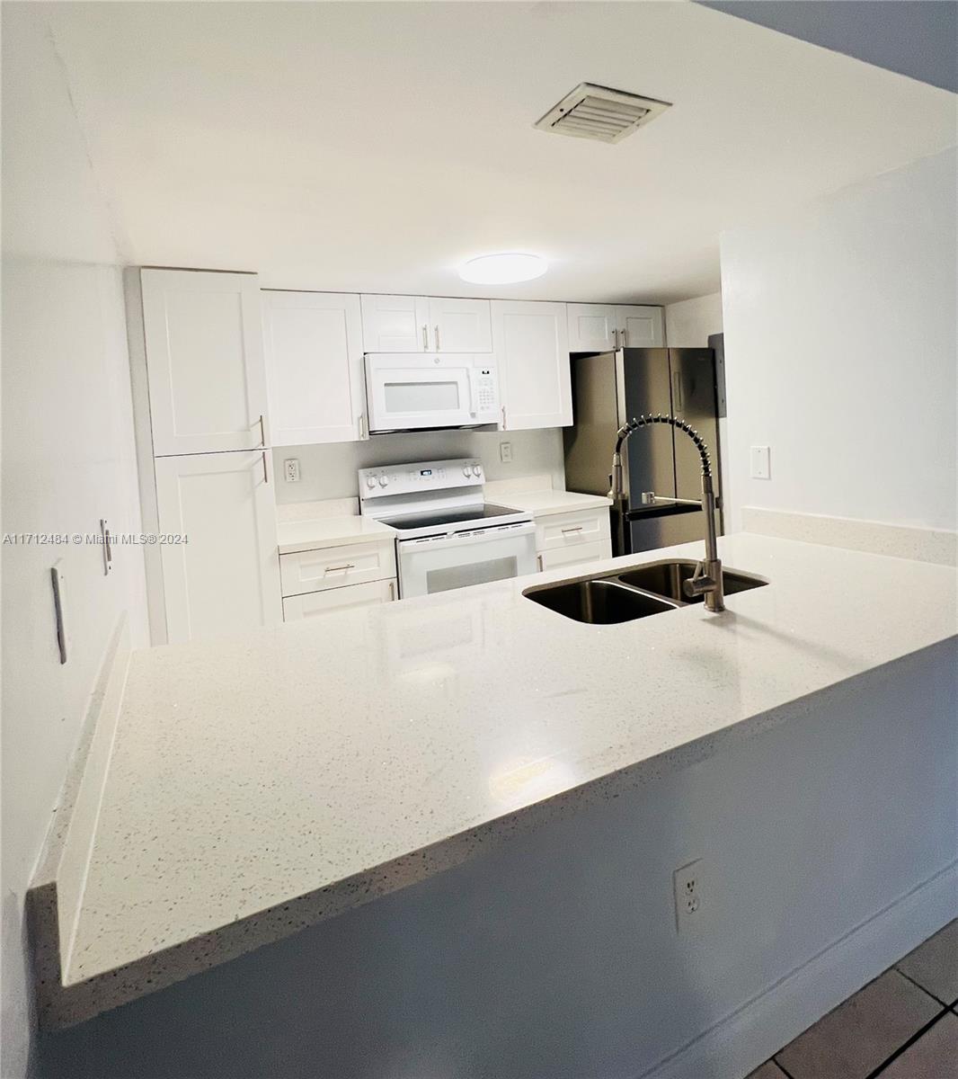 a kitchen with kitchen island a sink a stove and white cabinets