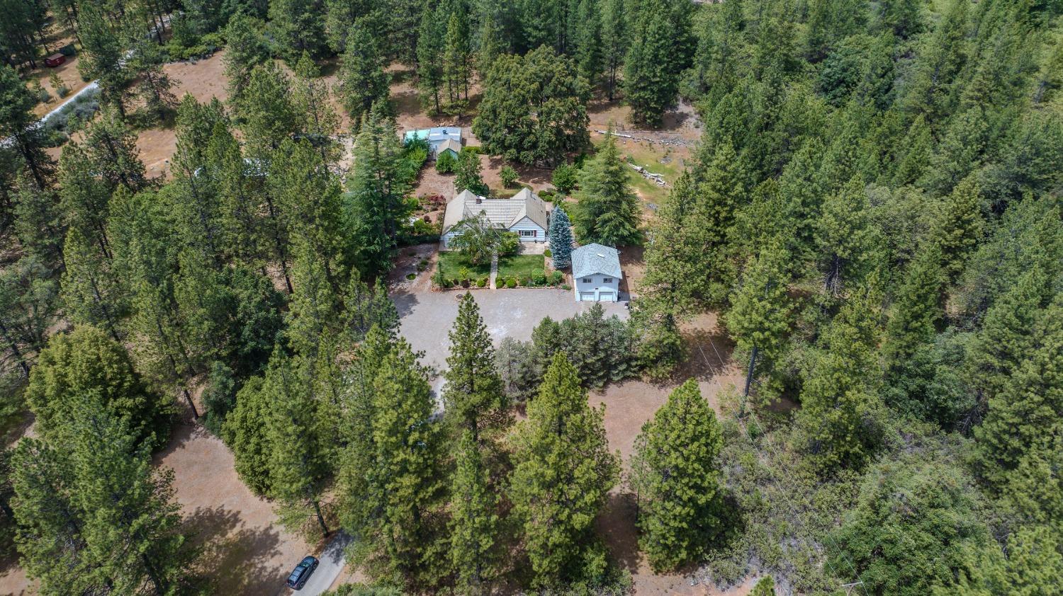 an aerial view of residential house with outdoor space and trees all around