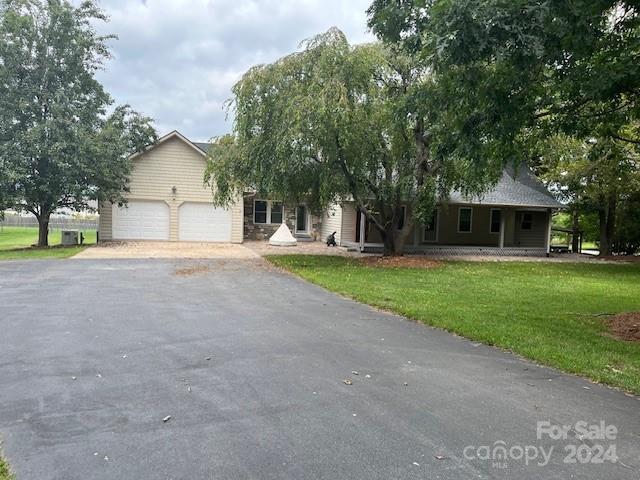 a view of a house with a yard and large tree