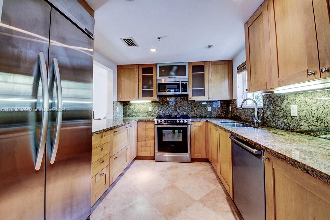 a kitchen with stainless steel appliances granite countertop a refrigerator and a sink