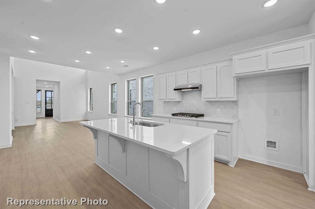 a large white kitchen with kitchen island a sink a stove and a refrigerator