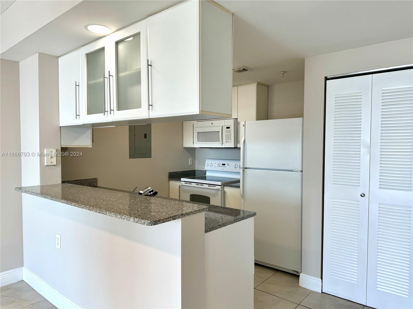 a kitchen with stainless steel appliances granite countertop a refrigerator a sink and white cabinets