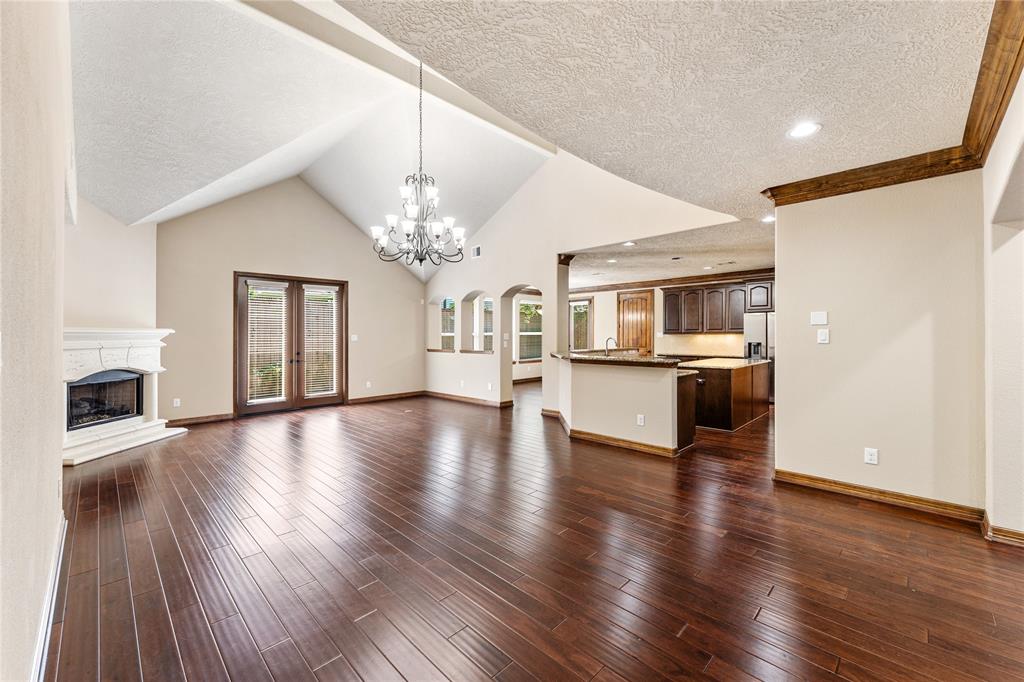 Huge Living Room with stunning chandelier, vaulted ceiling, and french doors access the backyard.