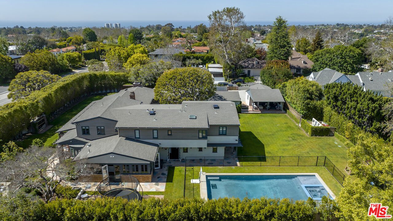 an aerial view of a house with swimming pool and large trees