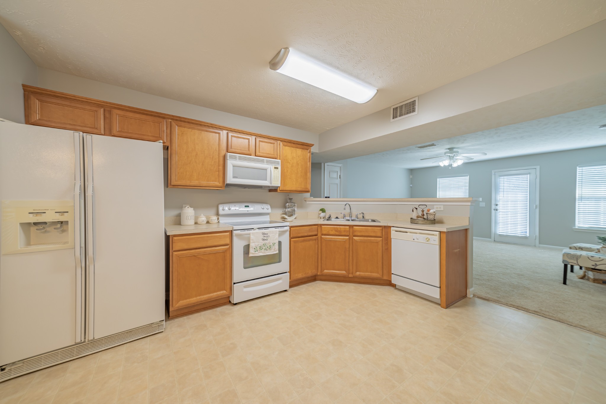 a large white kitchen with a refrigerator a sink a stove a dining table and chairs