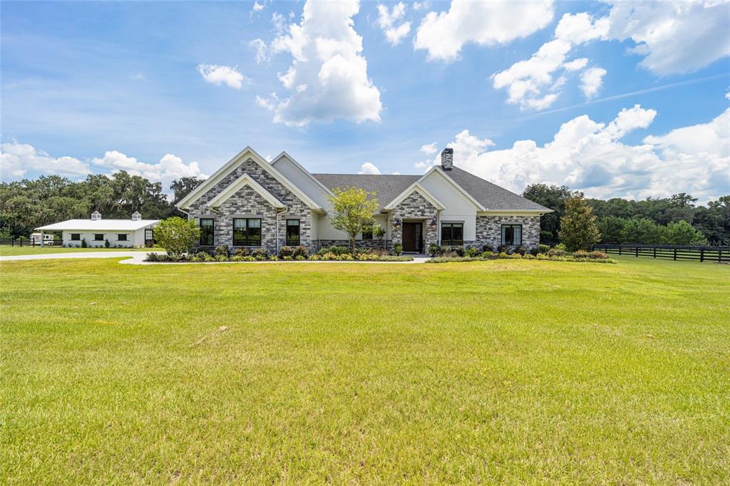 a front view of house with yard green space and lake view in back