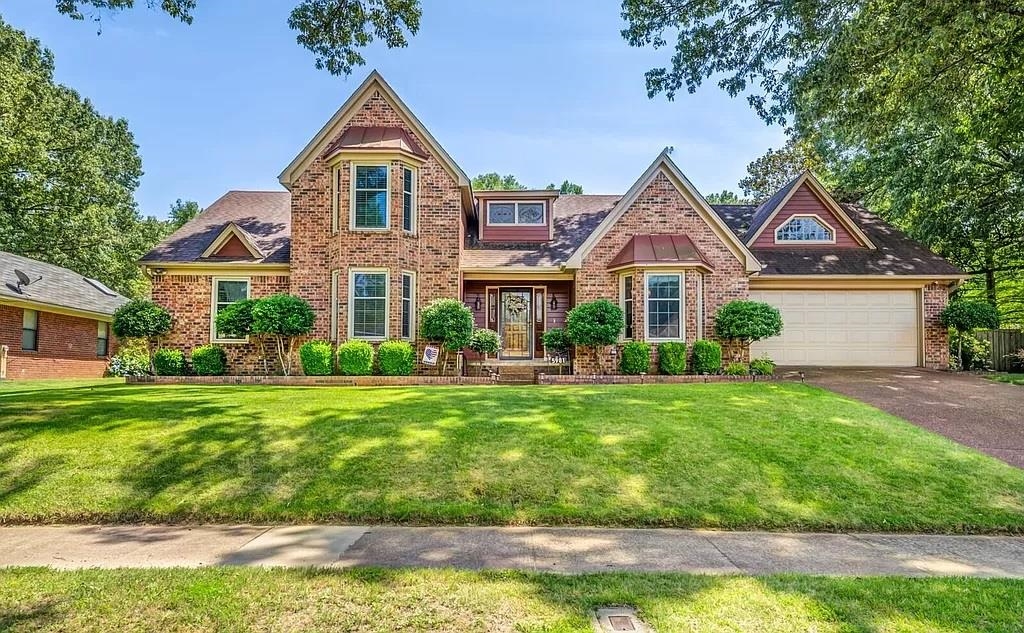 View of front of property featuring a front yard and a garage