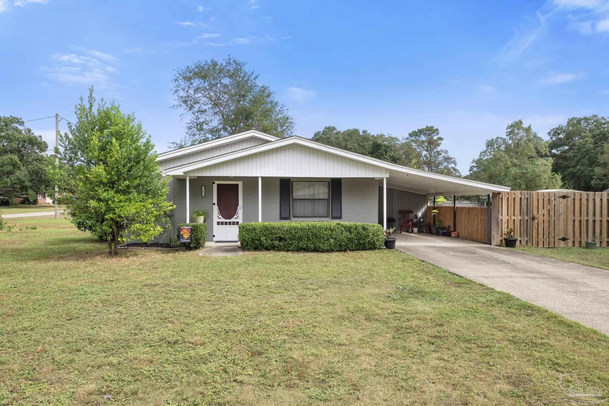 a front view of house with yard and trees in the background