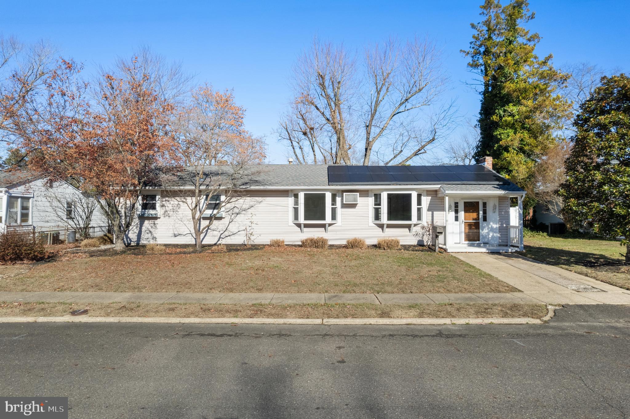 a front view of a house with a dirt yard and a large tree