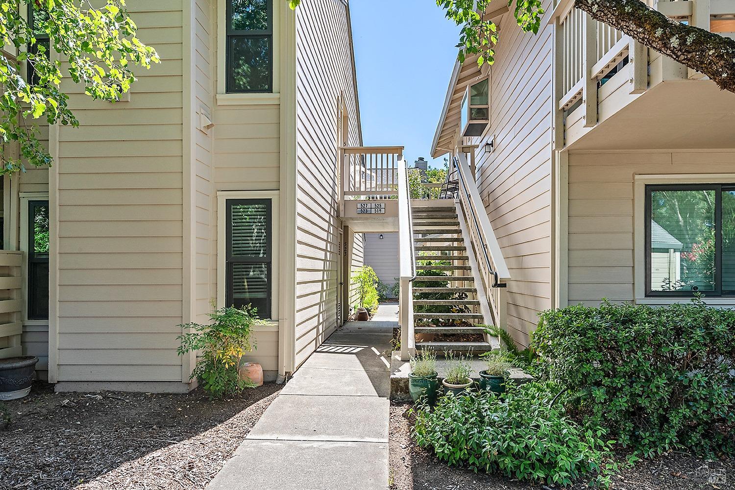 a view of a house with stairs and a yard with plants