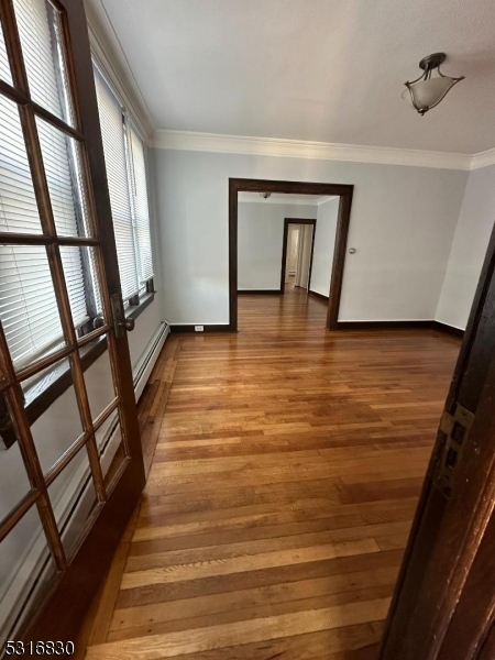 a view of an empty room with wooden floor and furniture