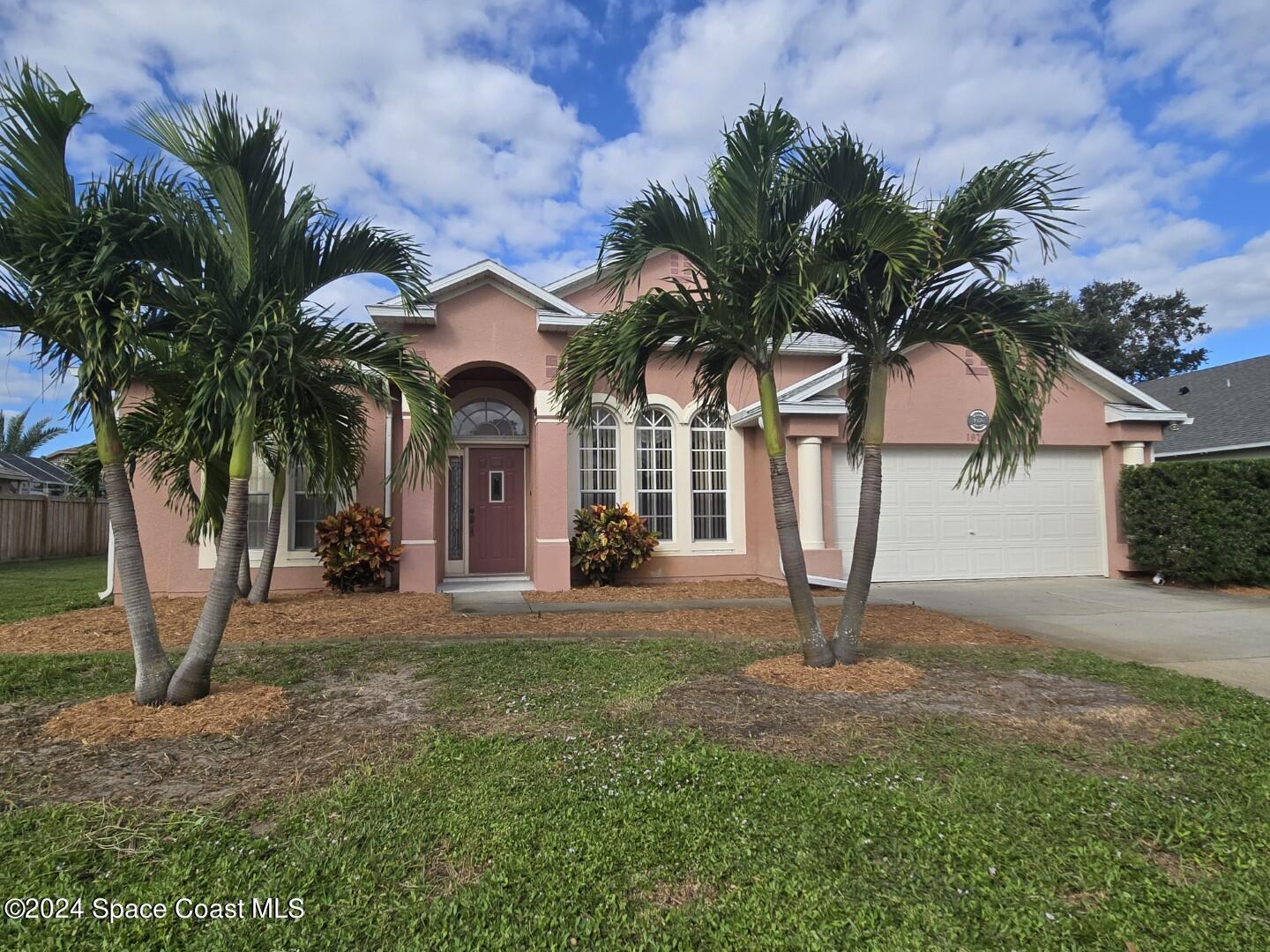 a view of a house with a yard and palm trees