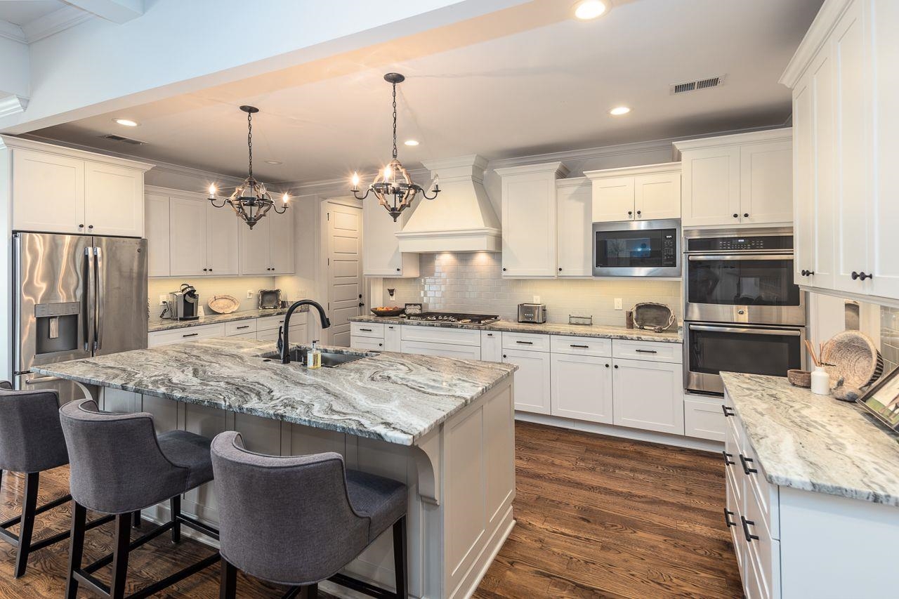 a kitchen with kitchen island granite countertop a sink cabinets and wooden floor