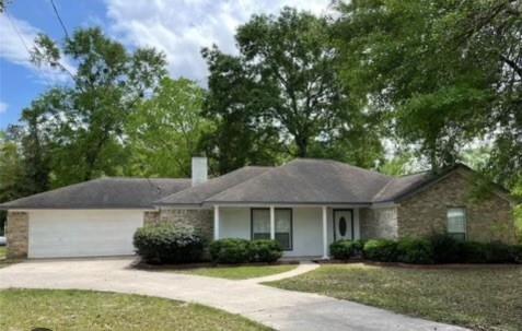 a front view of a house with a garden and trees