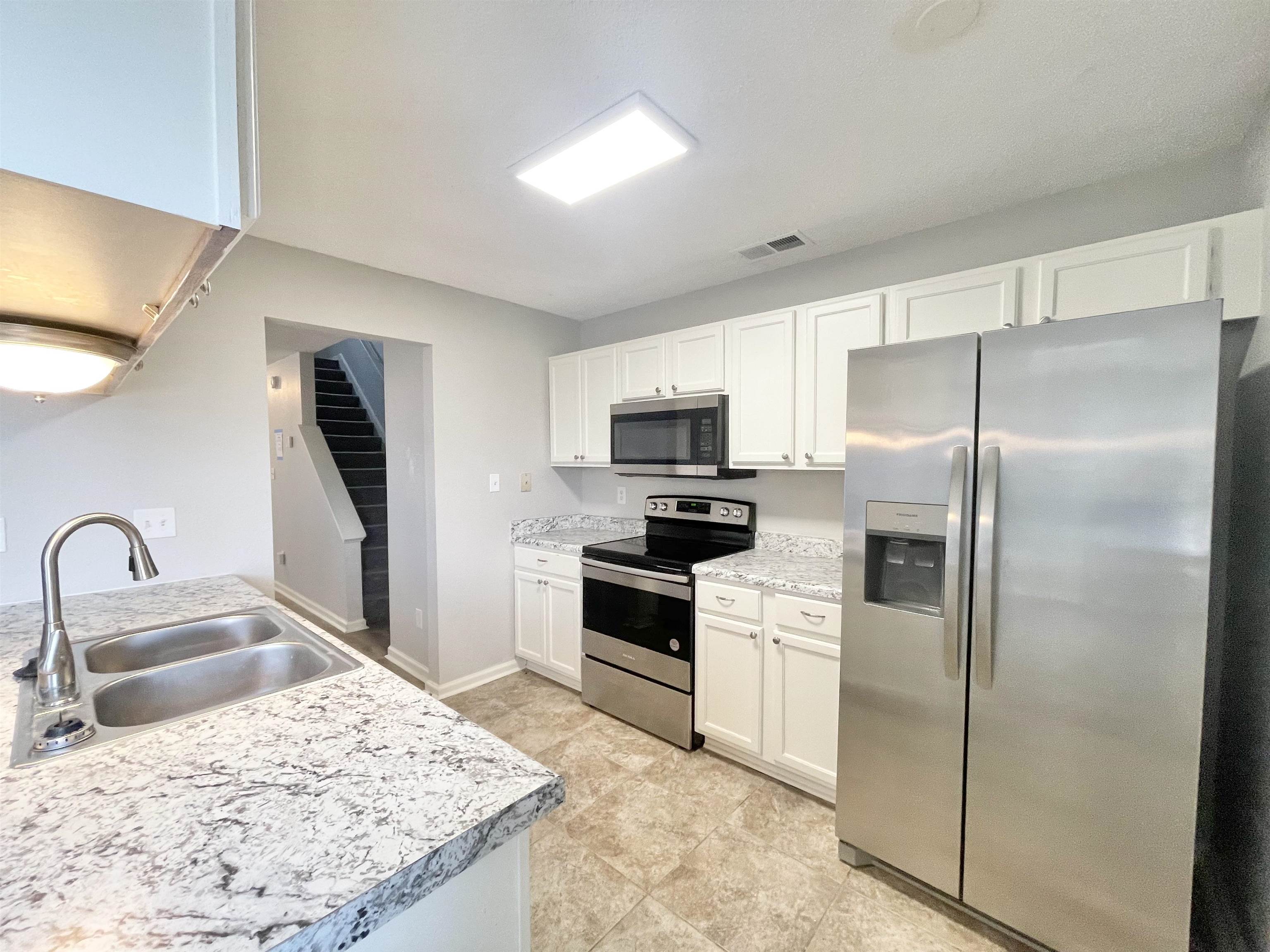 a kitchen with stainless steel appliances kitchen island a refrigerator sink and stove