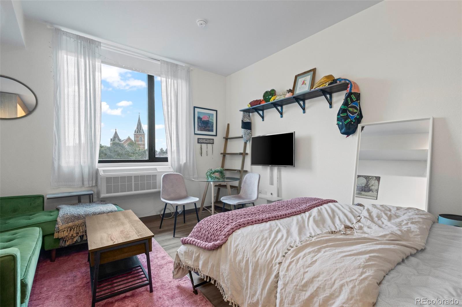 a bedroom with a bed a window and flat screen tv