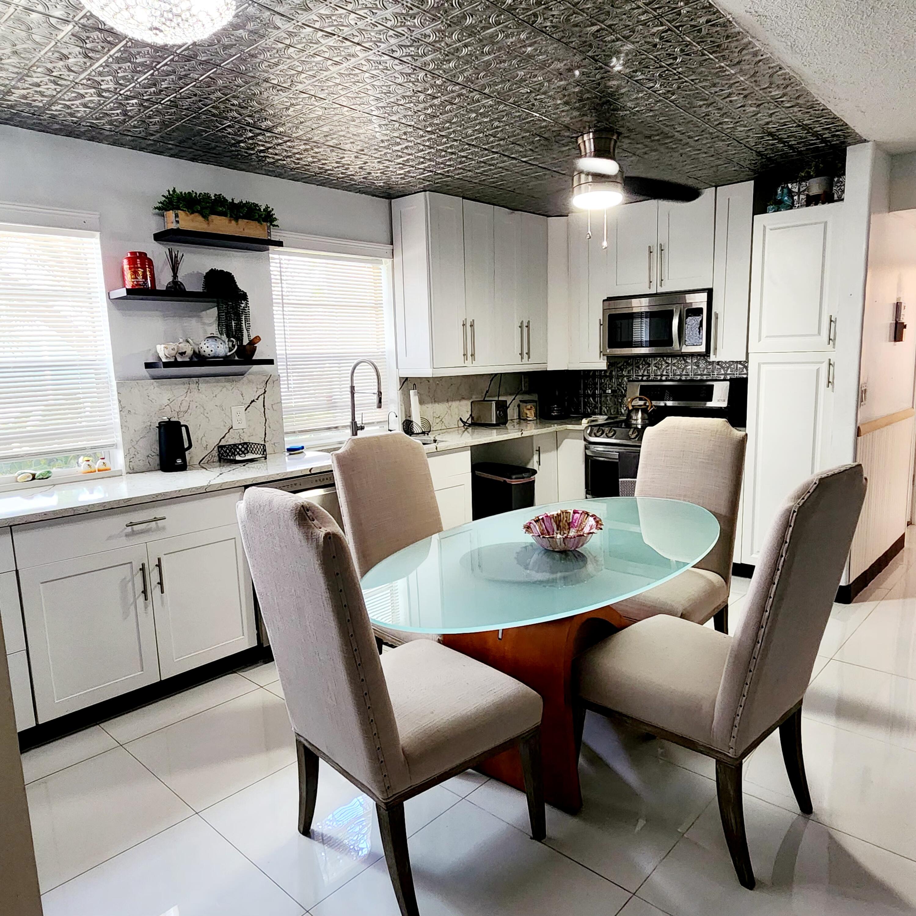 a kitchen with stainless steel appliances granite countertop a table chairs a microwave a sink and a refrigerator