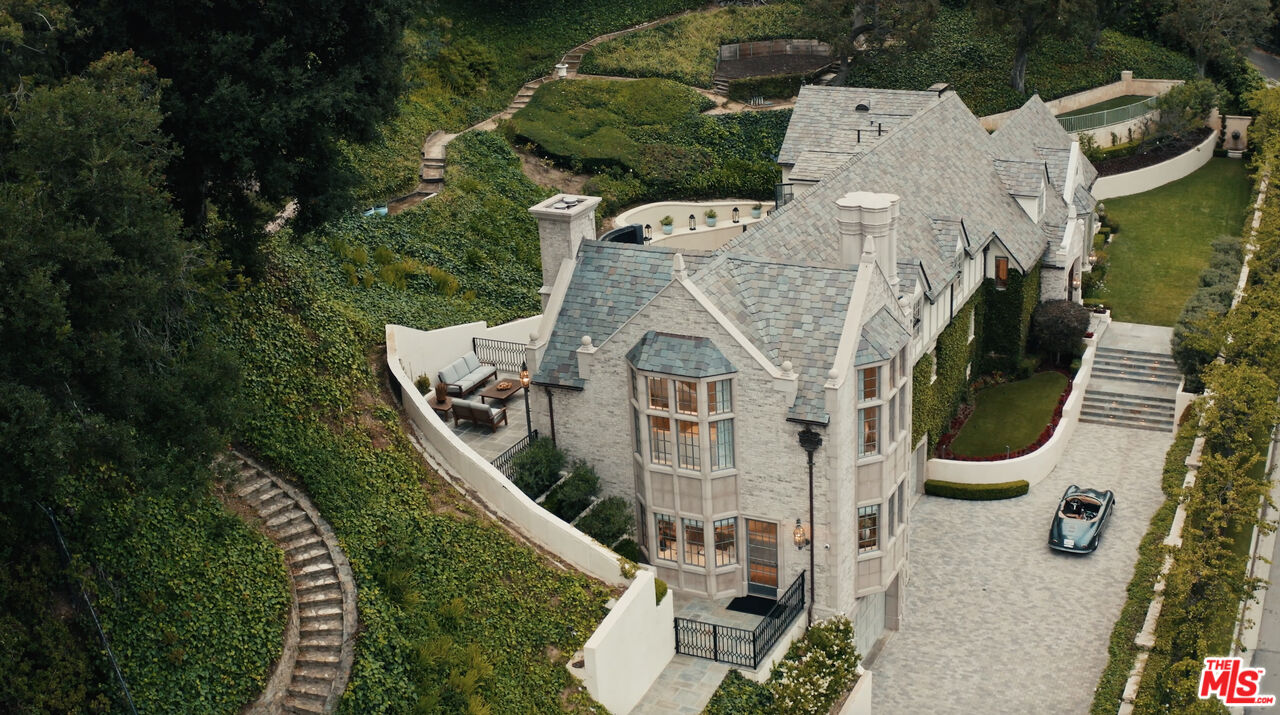 an aerial view of a house with swimming pool and large trees