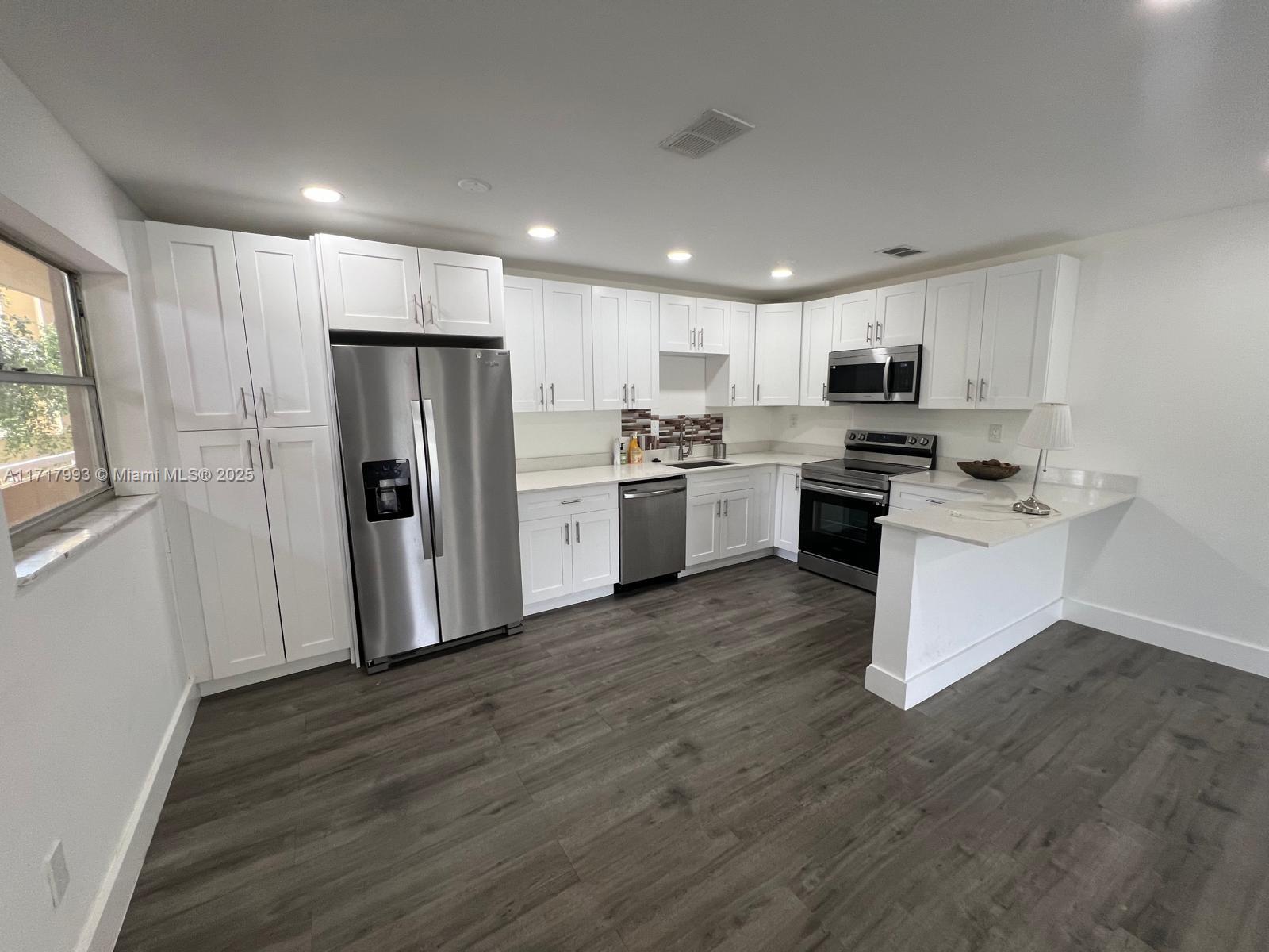 a kitchen with kitchen island granite countertop stainless steel appliances a refrigerator sink and microwave