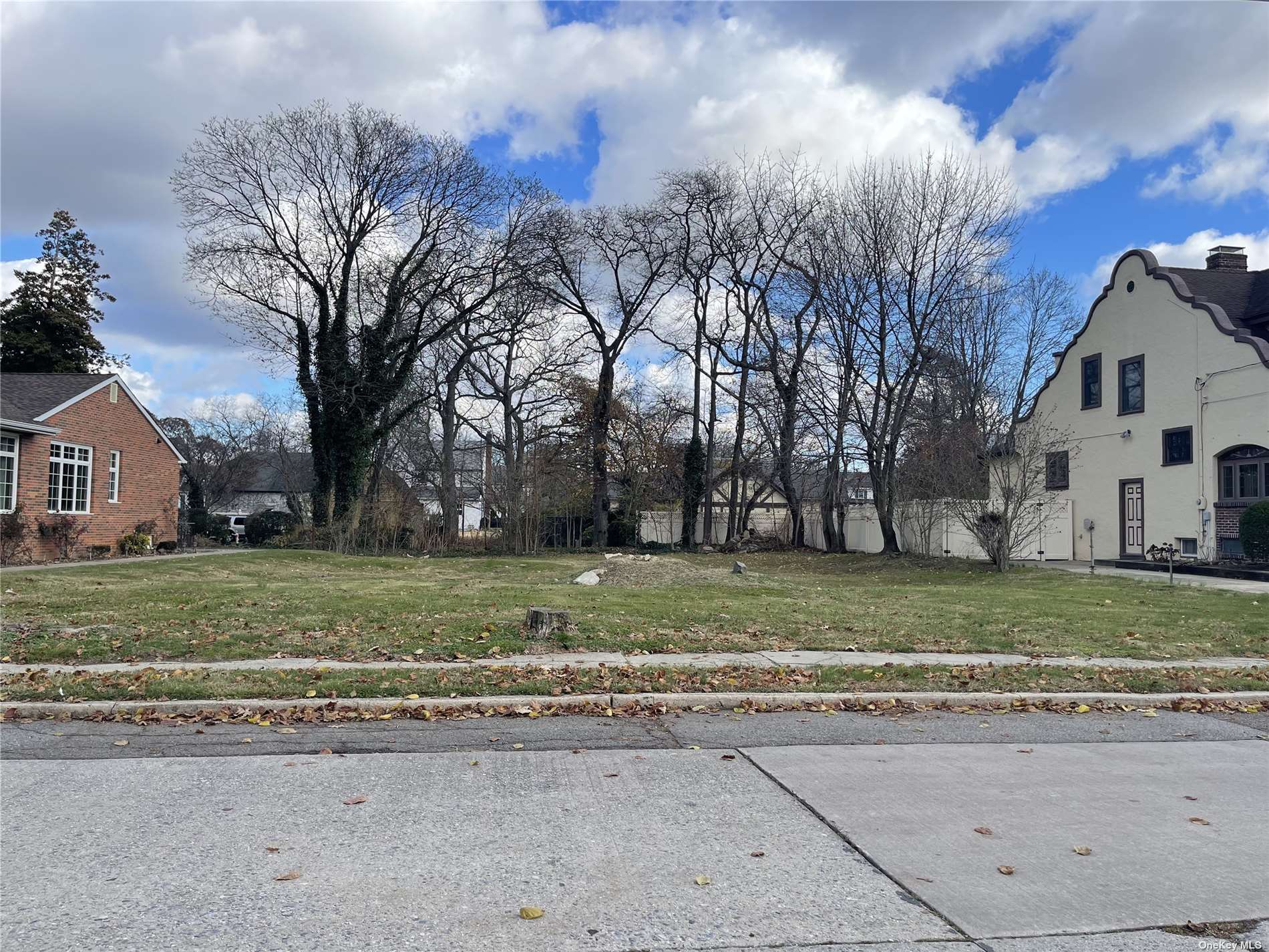 a view of a white house next to a yard with big trees