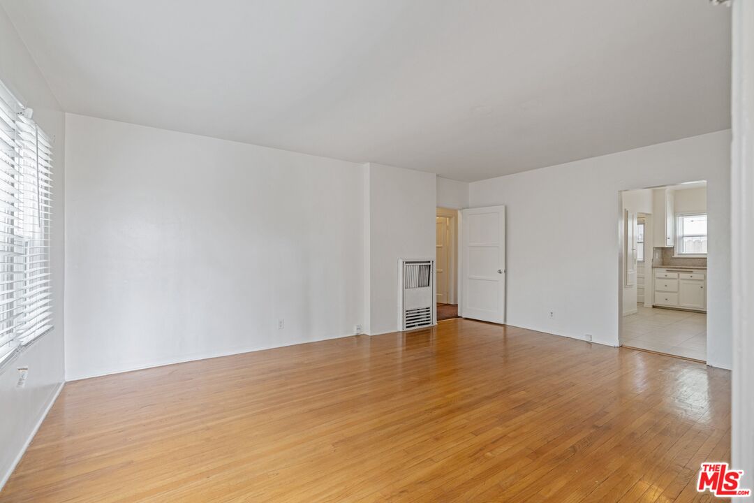 a view of an empty room with wooden floor and a window