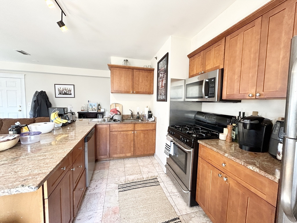 a kitchen with stainless steel appliances granite countertop a stove a sink and a refrigerator