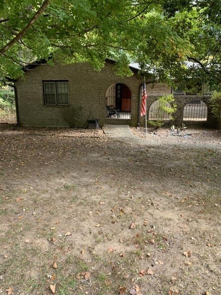 a view of house with yard and a trees