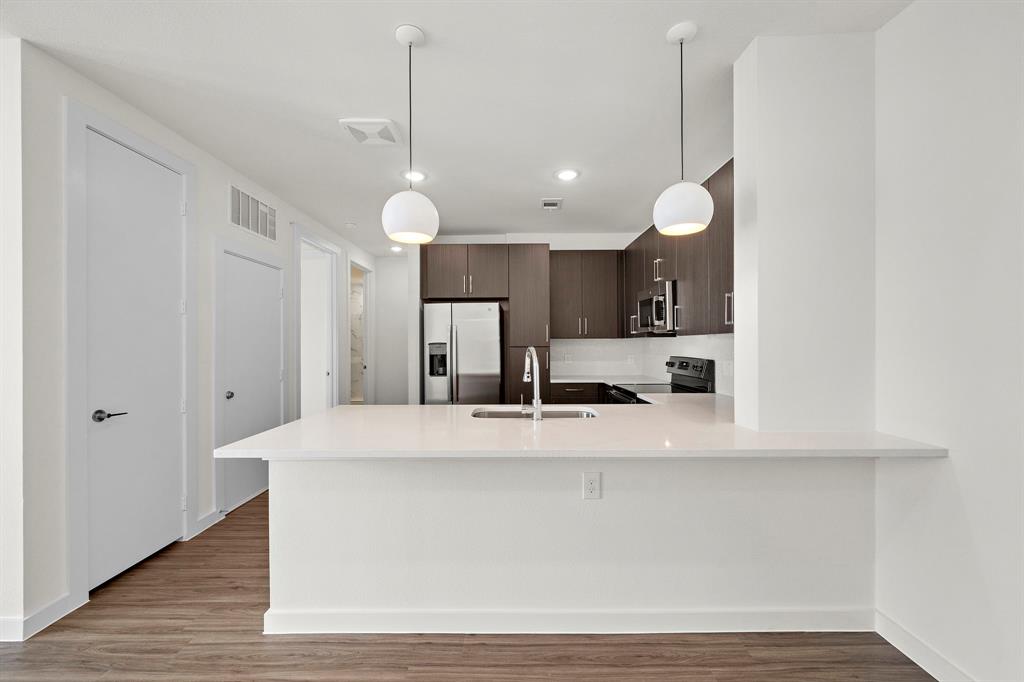 a large white kitchen with a large island oven a sink appliances and living room view