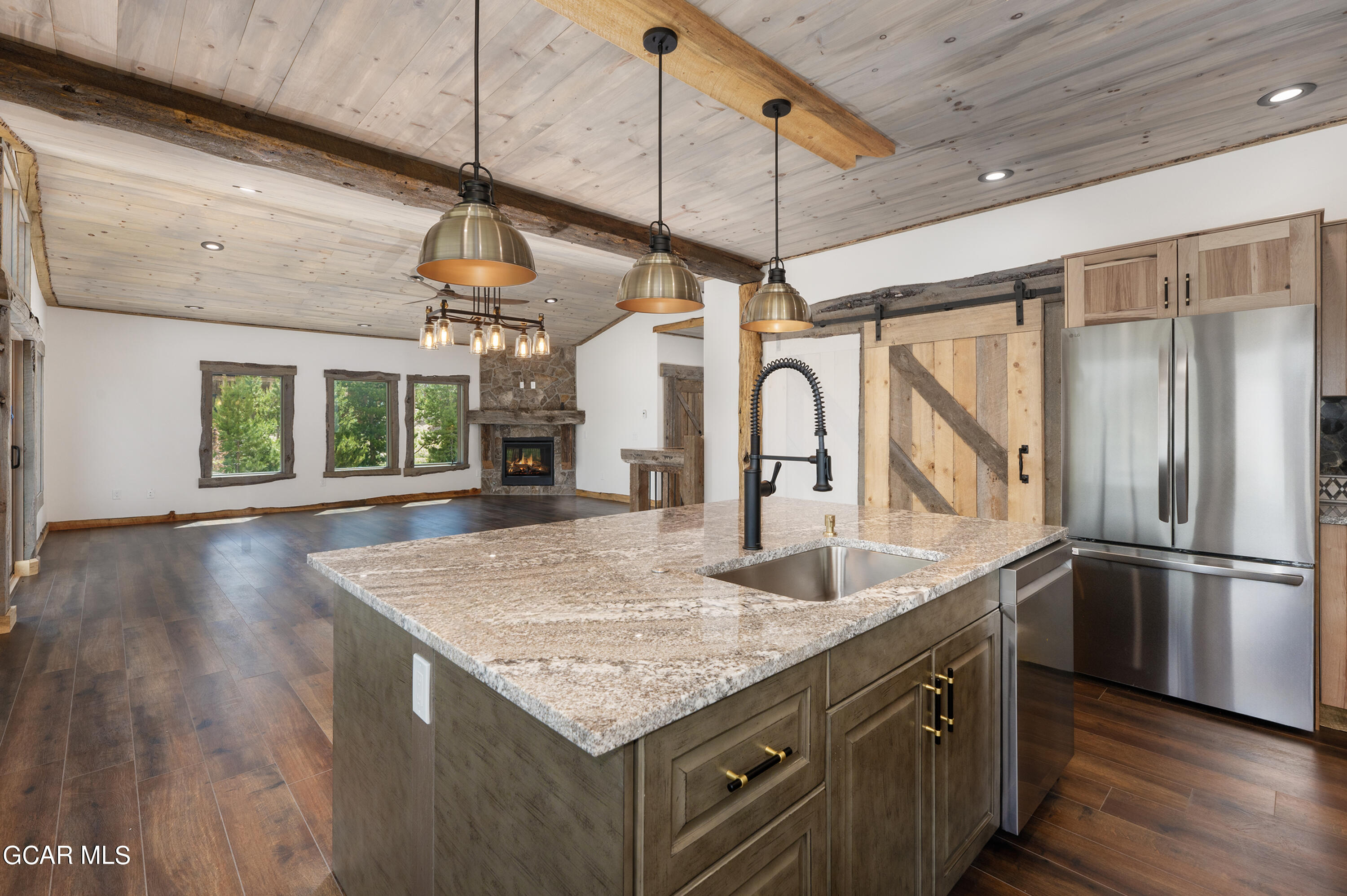 a kitchen with stainless steel appliances granite countertop a sink a refrigerator and wooden floor