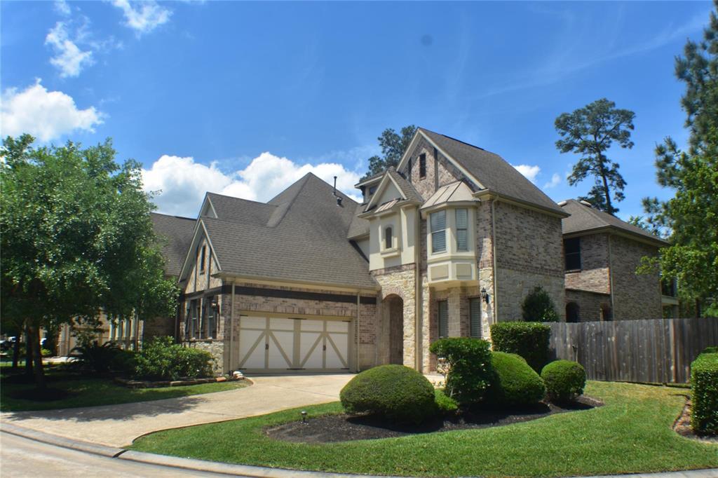 a view of a house with a small yard plants and a large tree