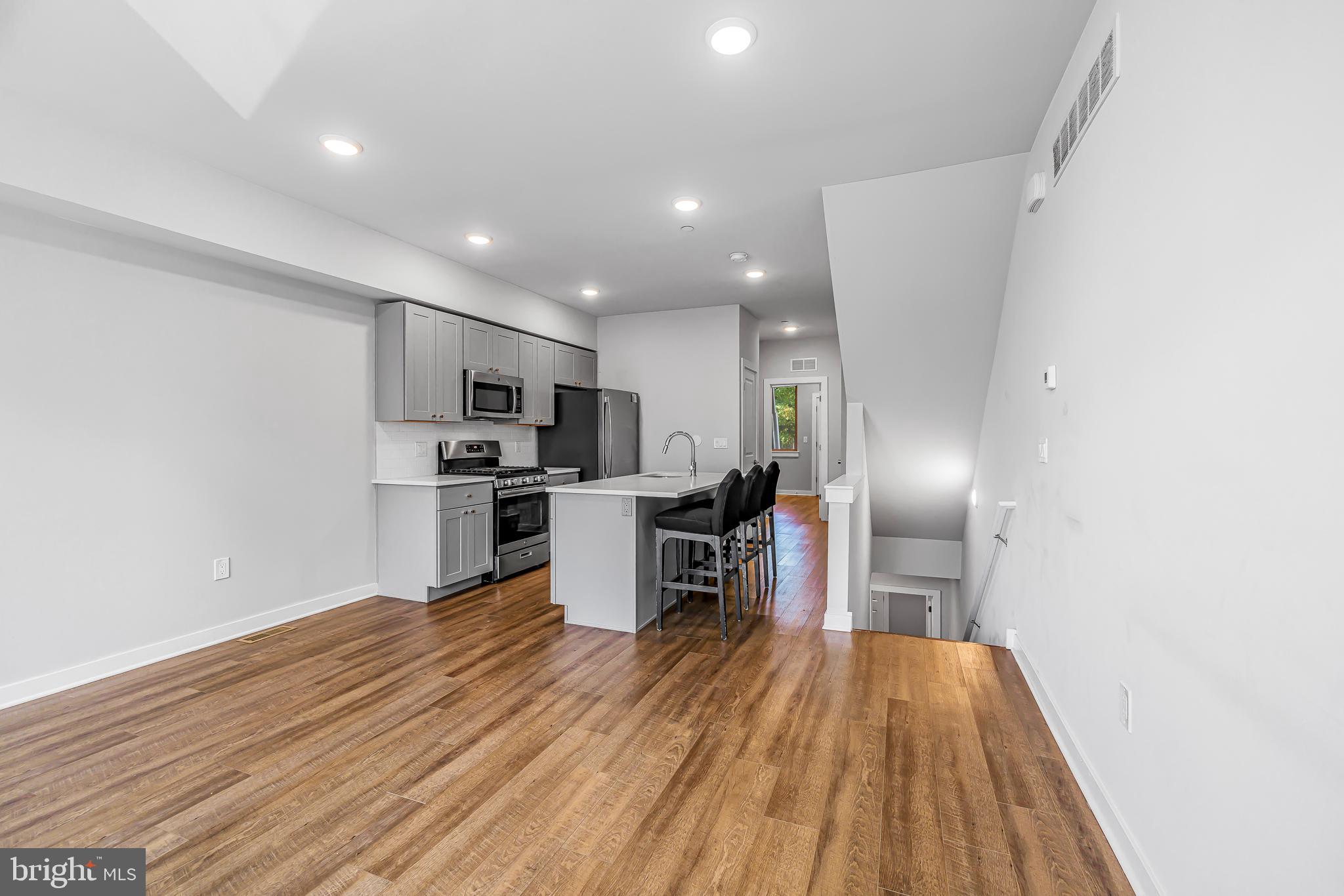 a kitchen with stainless steel appliances a refrigerator and a wooden floor