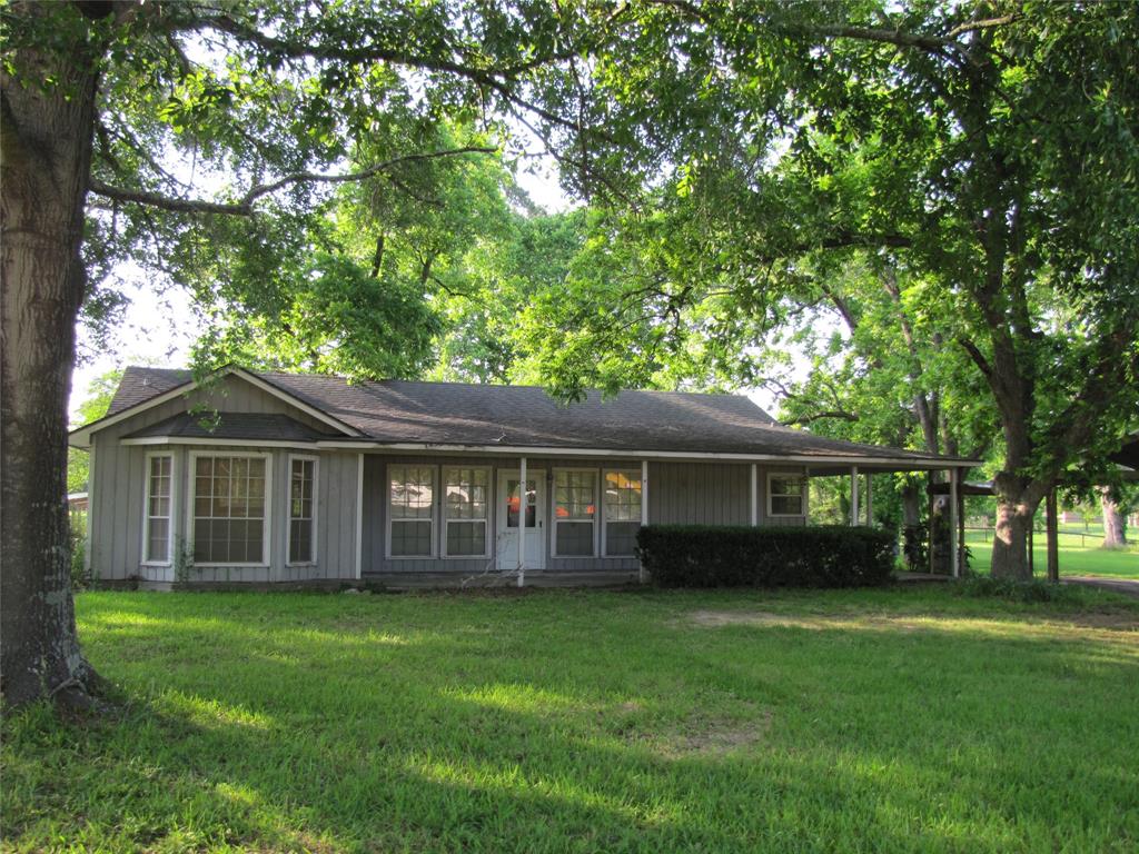 a view of a house with a yard and large trees