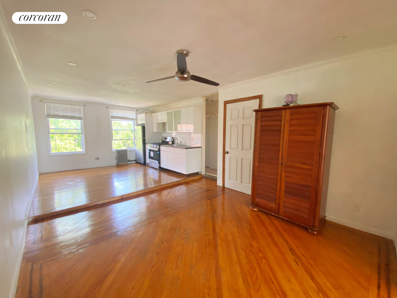 a view of an empty room with wooden floor and a window