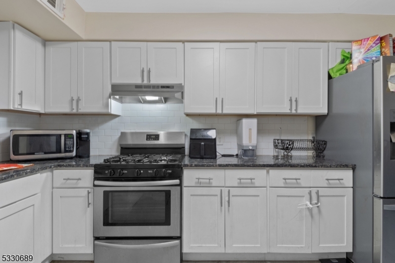 a kitchen with granite countertop white cabinets and stainless steel appliances