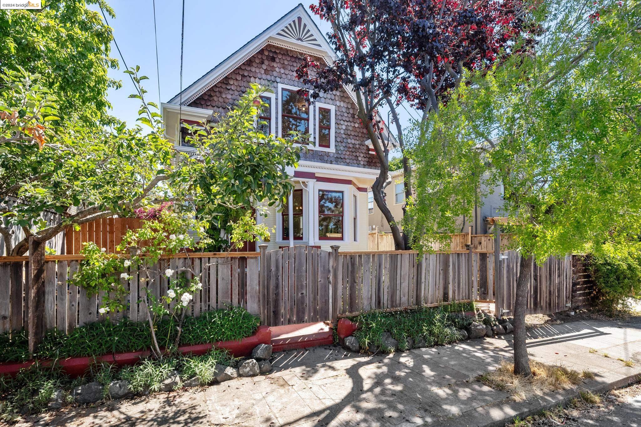 a view of a brick house with a small yard plants and large trees