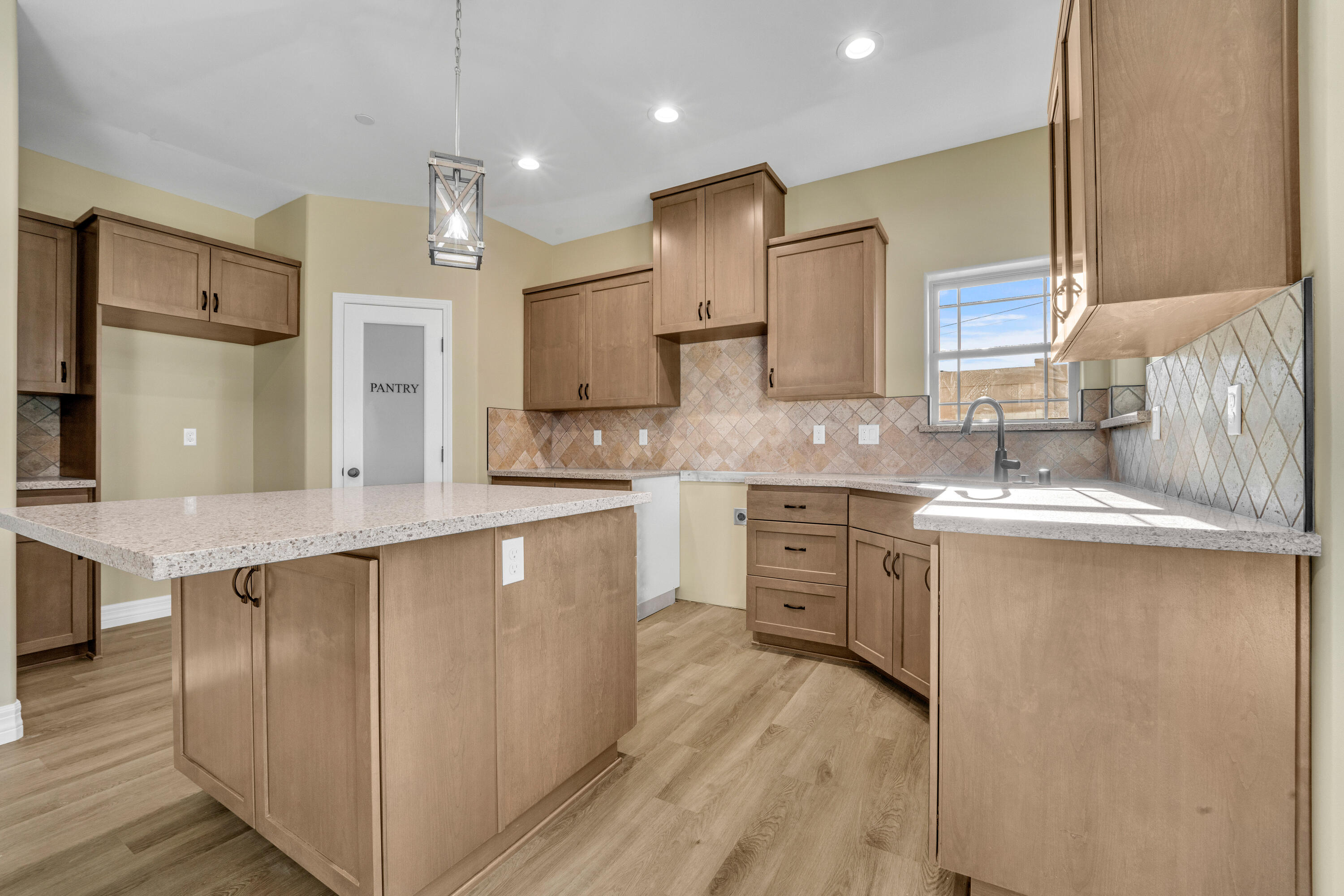 a large kitchen with cabinets a sink a center island stainless steel appliances and a window