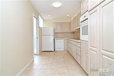 a kitchen with white cabinets and white appliances