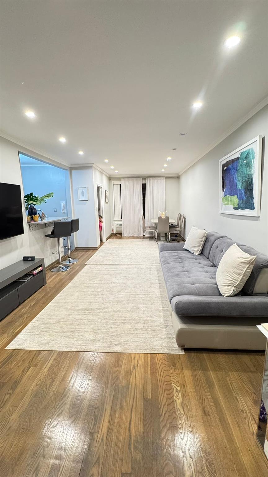 Living room featuring wood-type flooring and ornamental molding