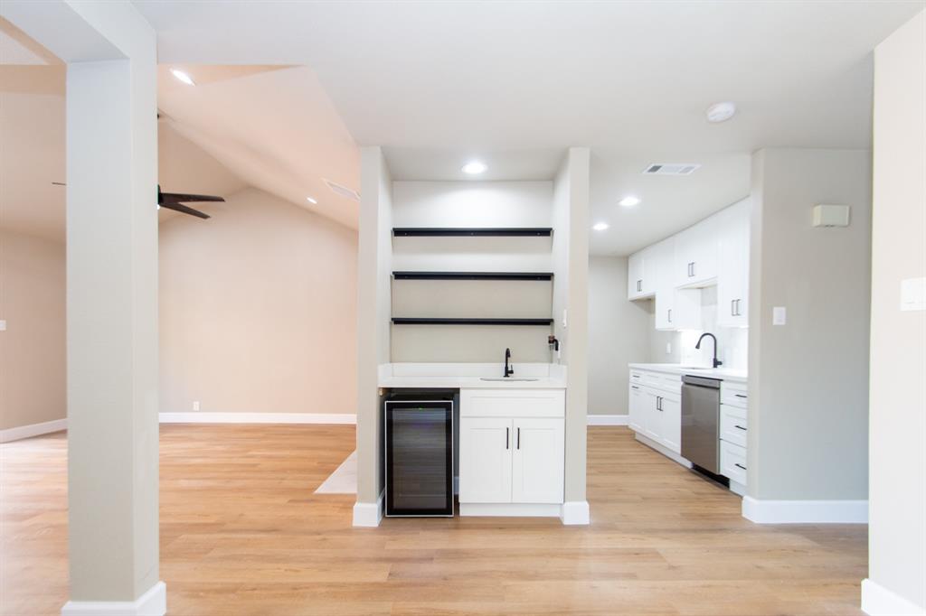 a large kitchen with a large counter top a sink stainless steel appliances and cabinets