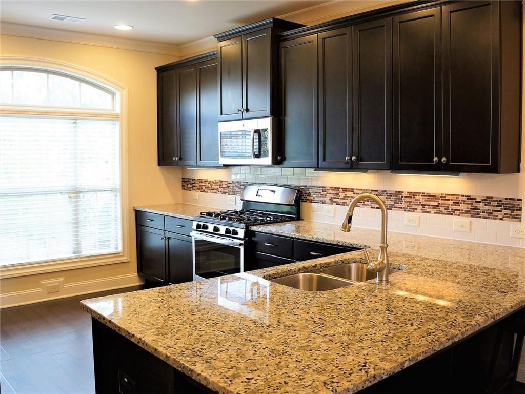 a kitchen with granite countertop a sink stove and refrigerator