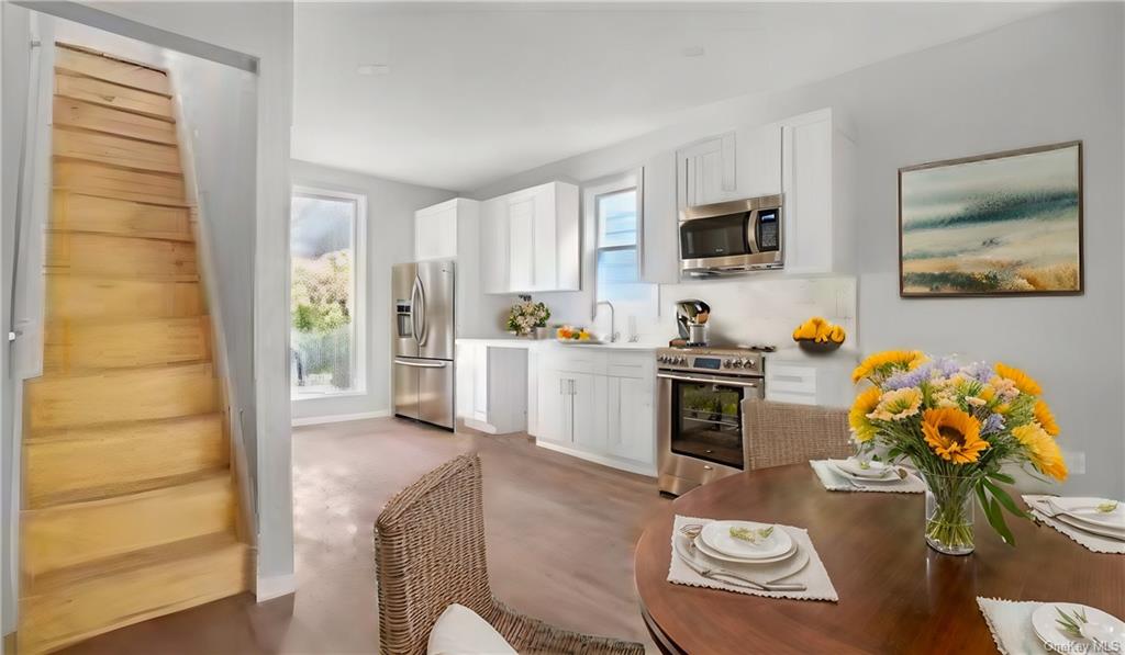 Kitchen with appliances with stainless steel finishes, a healthy amount of sunlight, and white cabinets