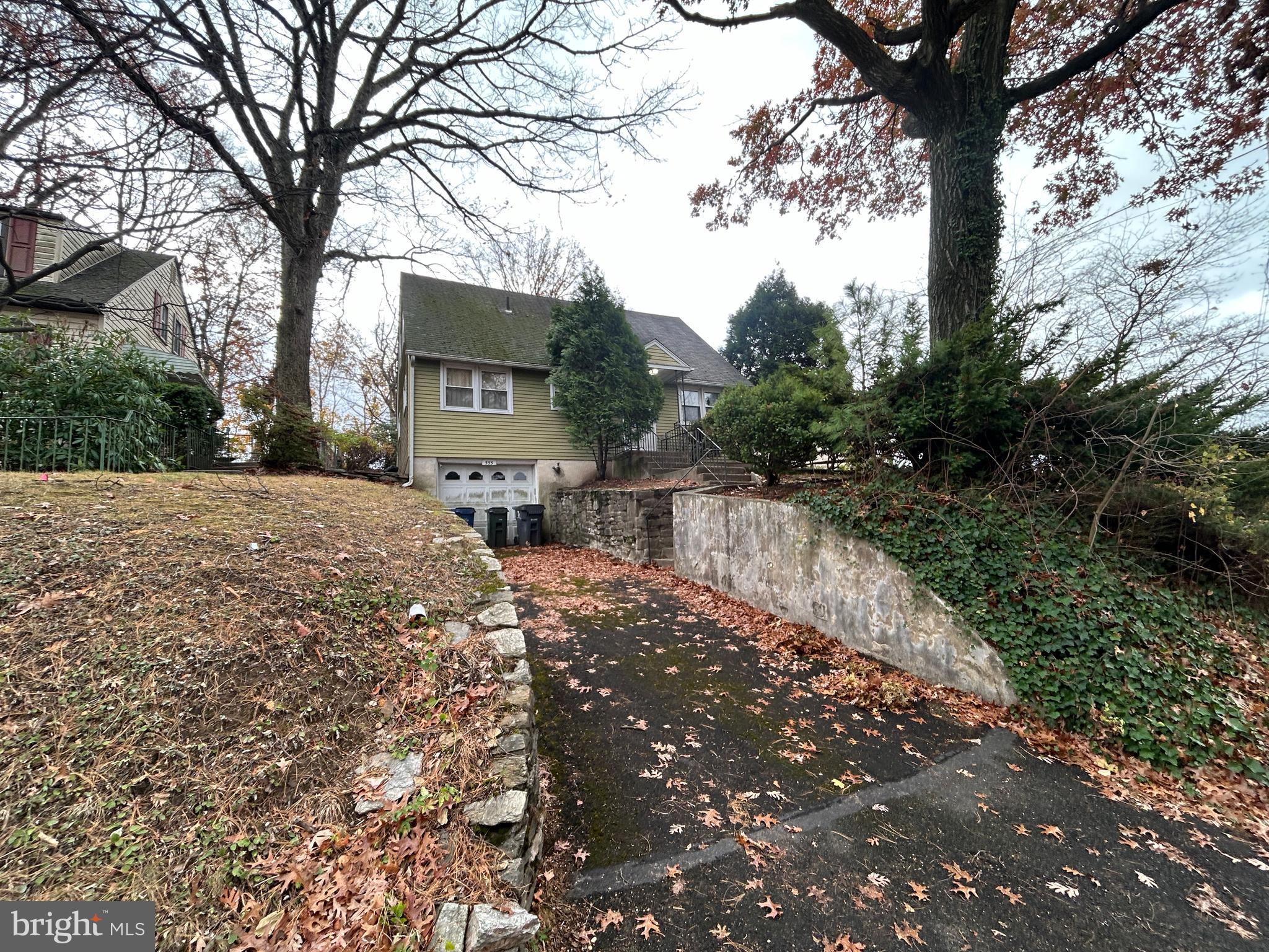 a pathway of a house with a yard and large trees