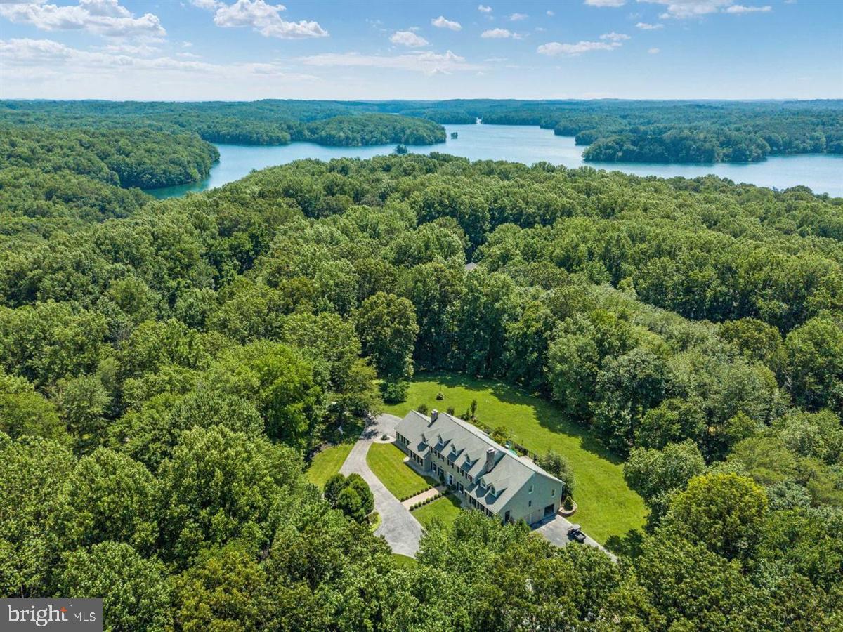 an aerial view of a residential houses with outdoor space and trees all around