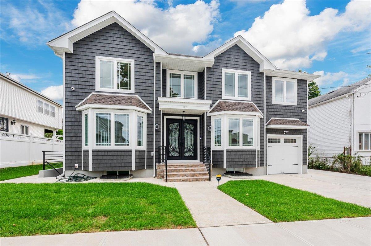 View of property featuring french doors, a garage, and a front lawn