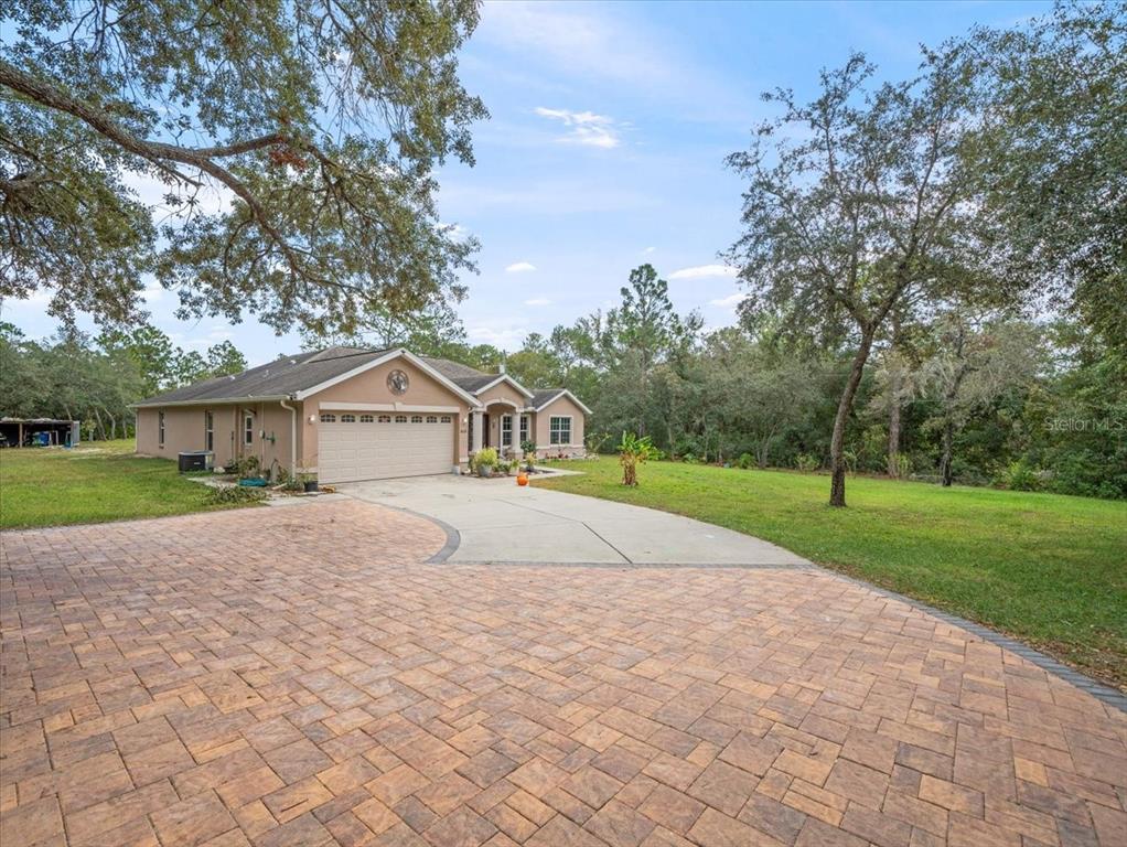 a view of a house with a yard and large trees