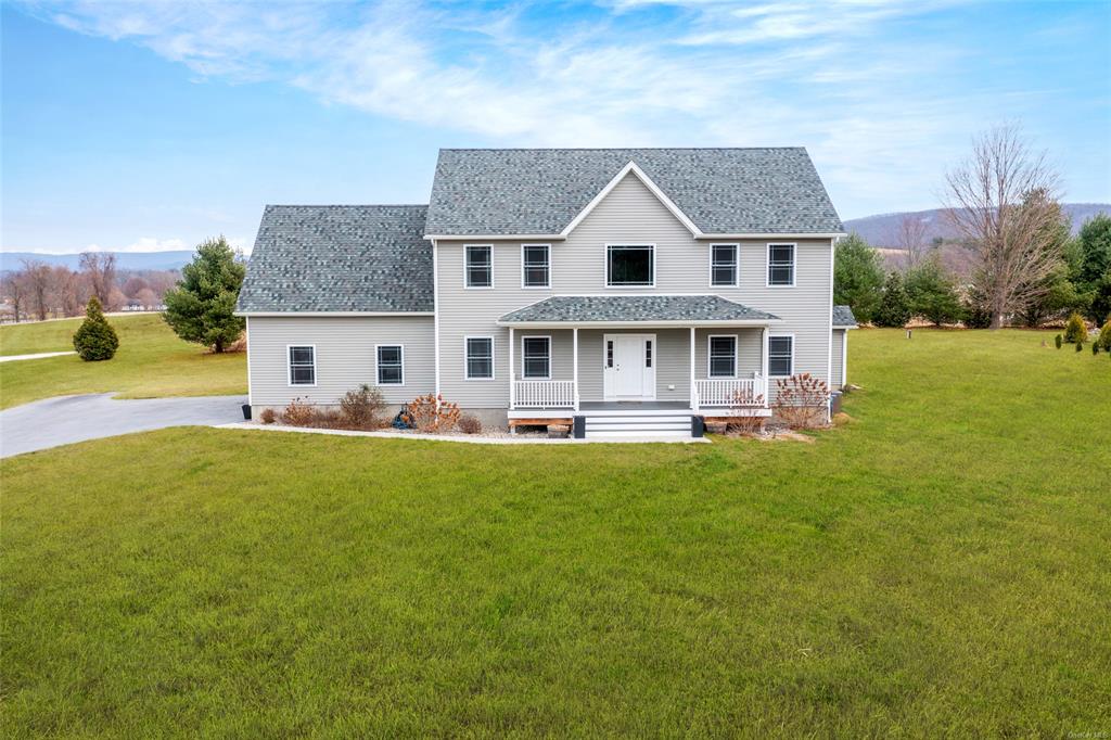 Colonial house with a mountain view, a porch, and a front lawn