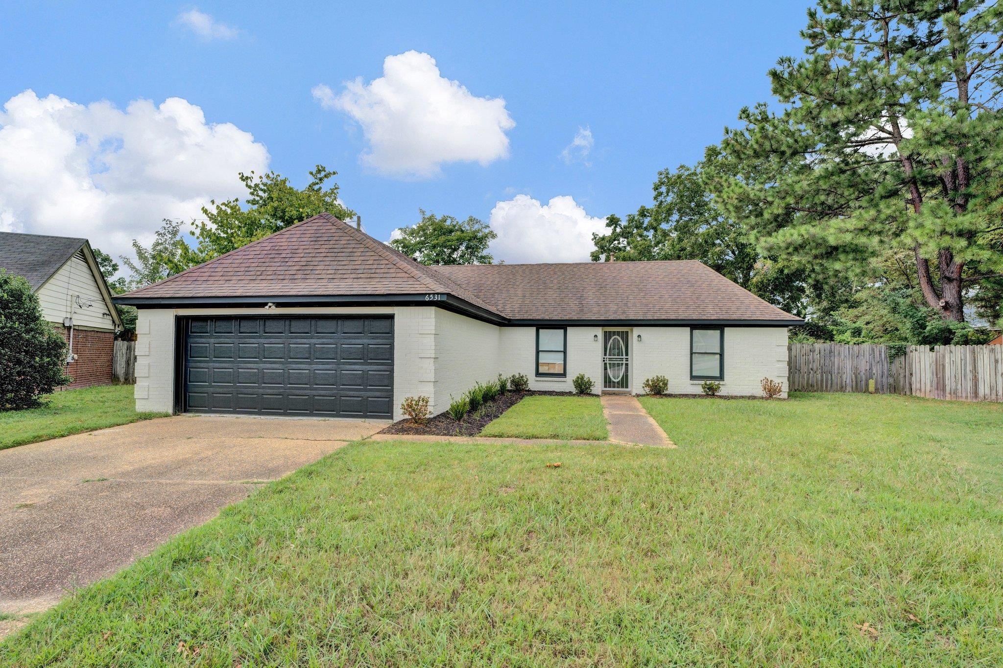 Single story home with a garage and a front lawn