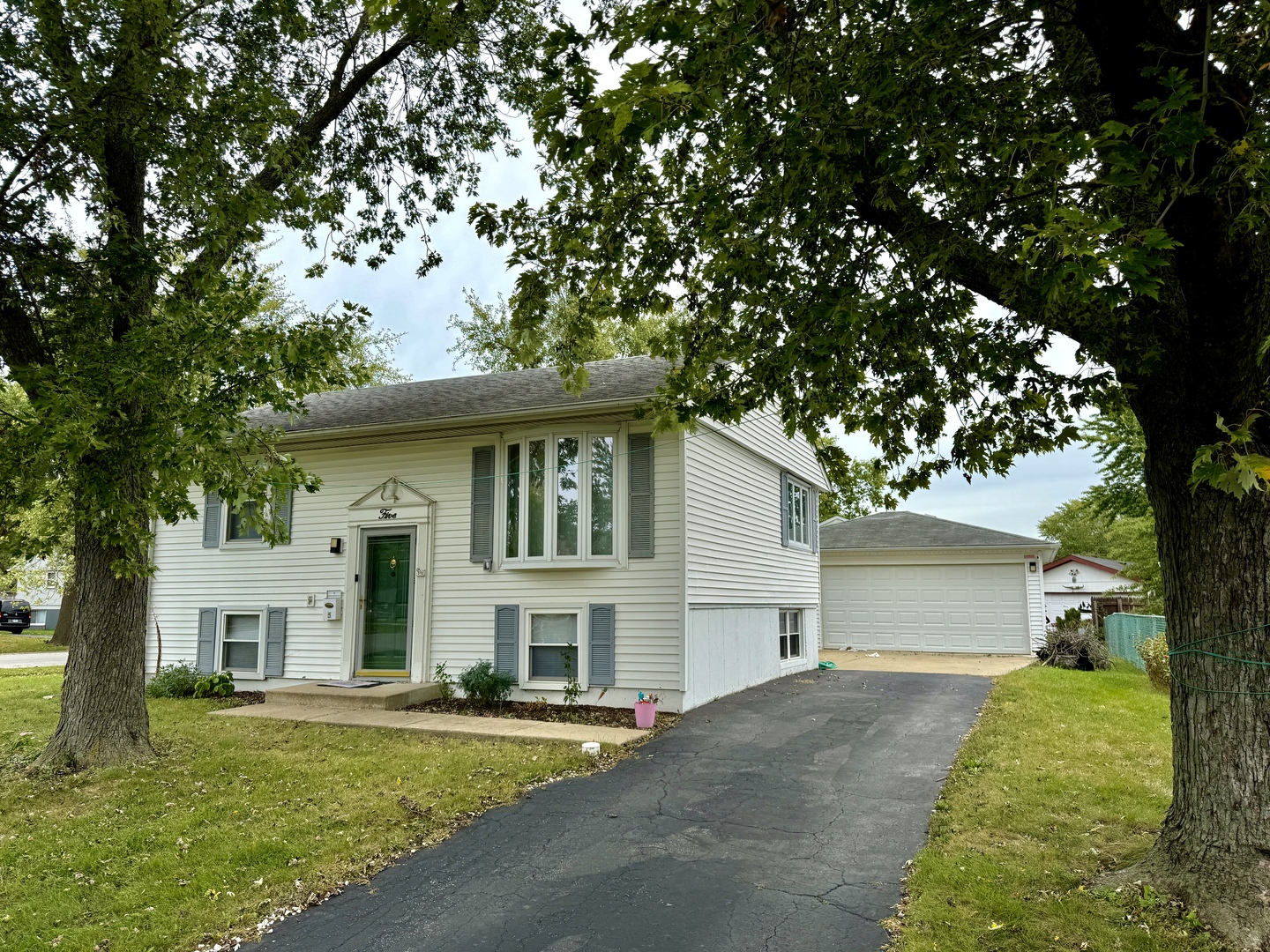 a front view of a house with a garden and trees